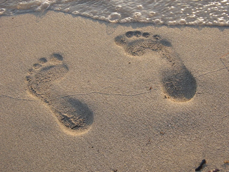 two footprints are seen in the sand at the beach