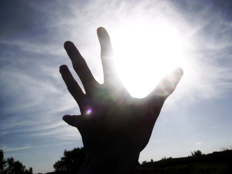a person reaching out to the sun with their hand