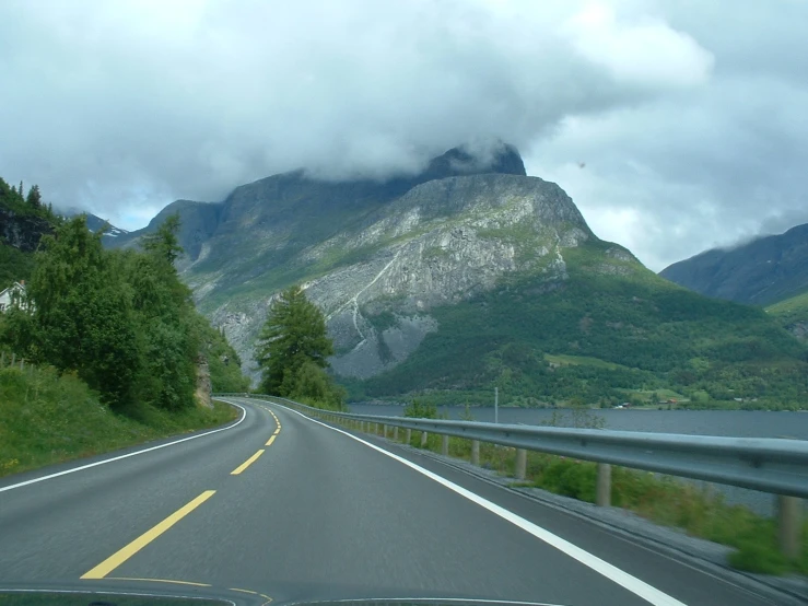 the long road is lined with mountains and grassy areas