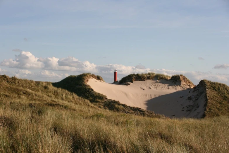 a lighthouse sitting on top of a sand dune