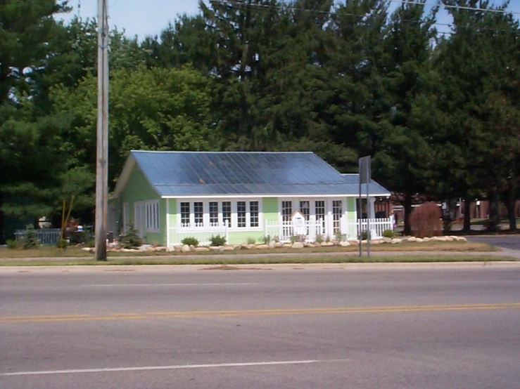 the house is next to the road near some trees