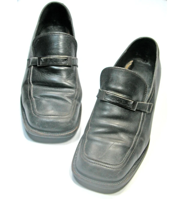 a closeup view of two black shoes on a white surface