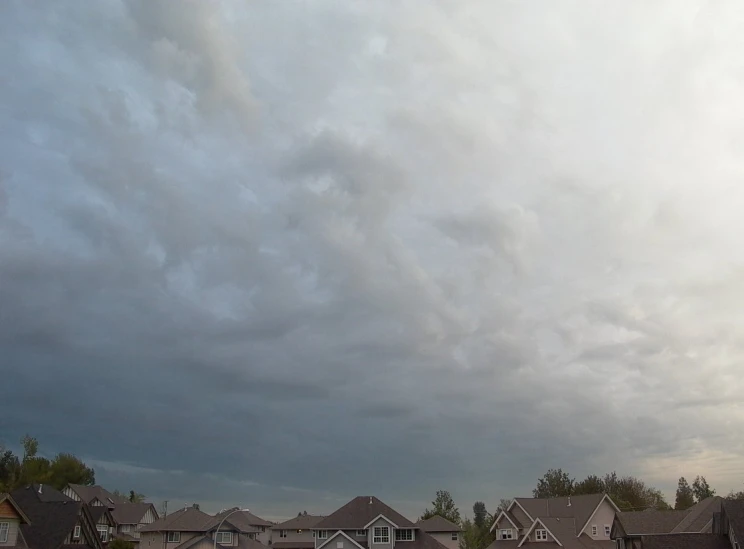 a group of houses in a residential area with a sky that has clouds behind them