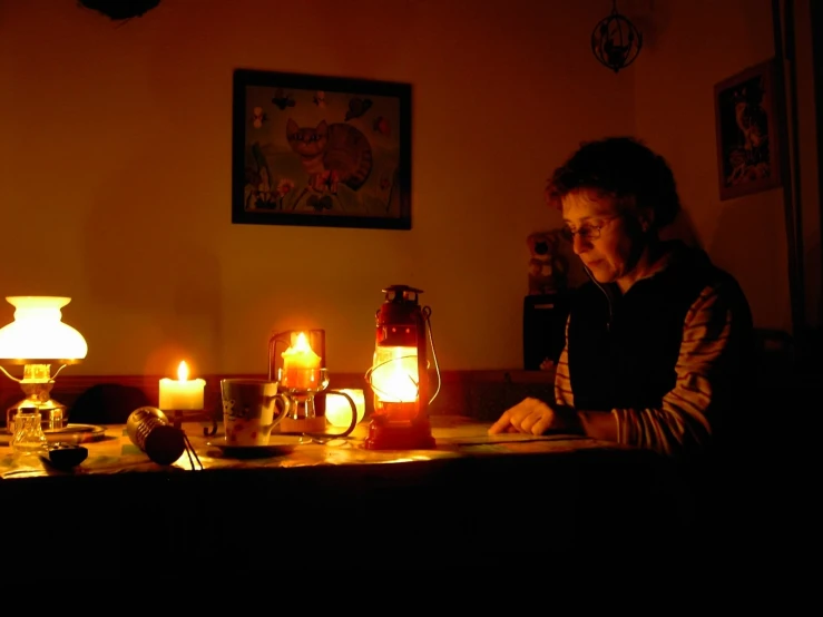 woman looking at lit candle light in a darkened room