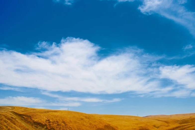 the desert is surrounded by golden hills and green grass