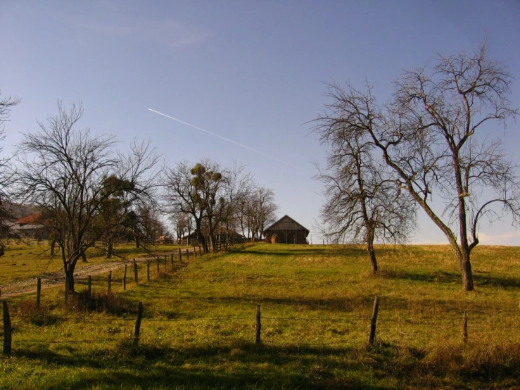 a very small house in the distance with a kite flying in the air