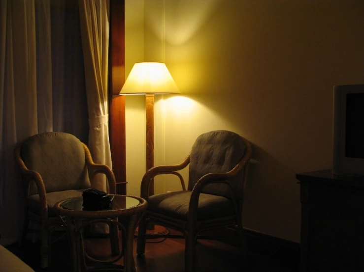 a room with two chairs next to the lamp