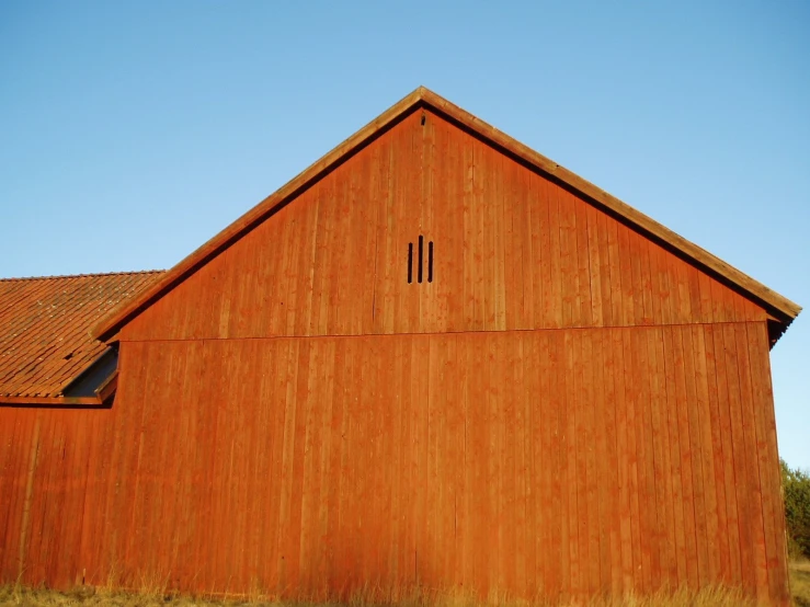 an old barn with a grass field and dirt ground