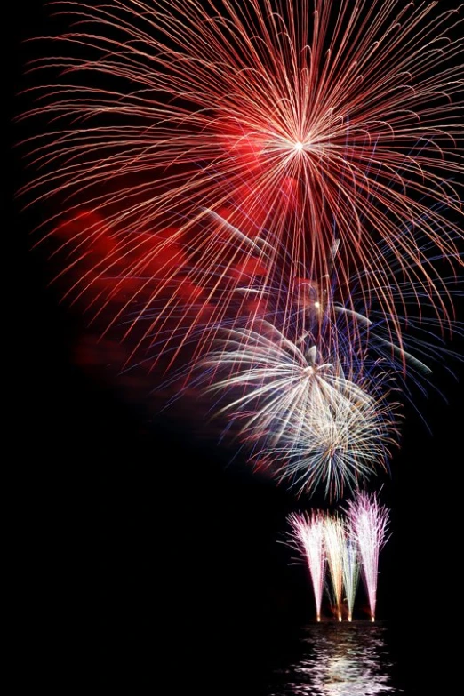 colorful fireworks exploding over water on black sky