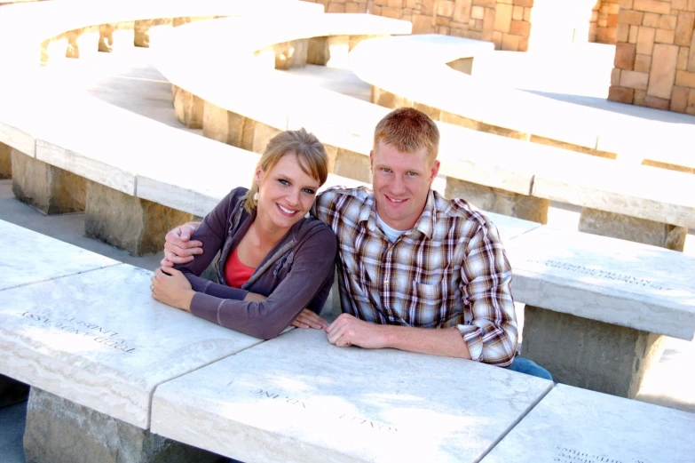 two people standing next to each other near stone benches