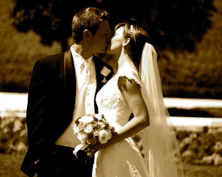 a bride and groom share a kiss in sepia tone