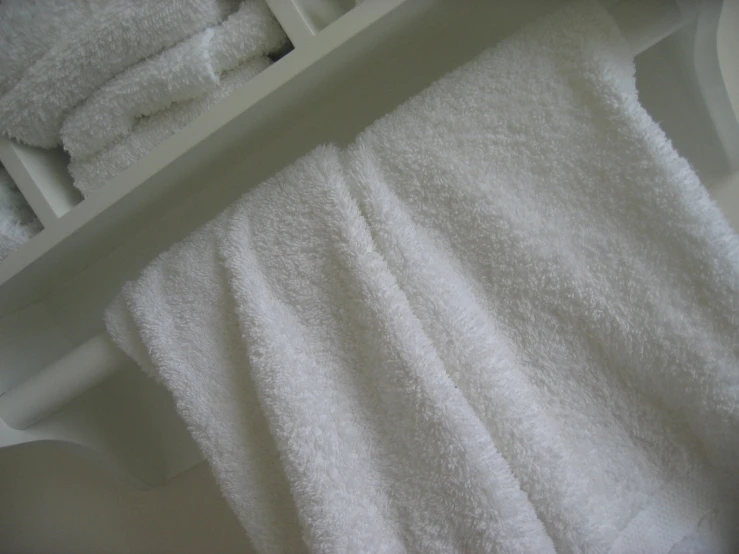 several white towels on a shelf lined up