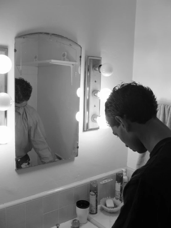 a man looking in the bathroom mirror with his reflection in the mirror