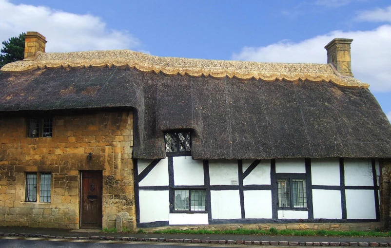 the black and white building has a thatched roof