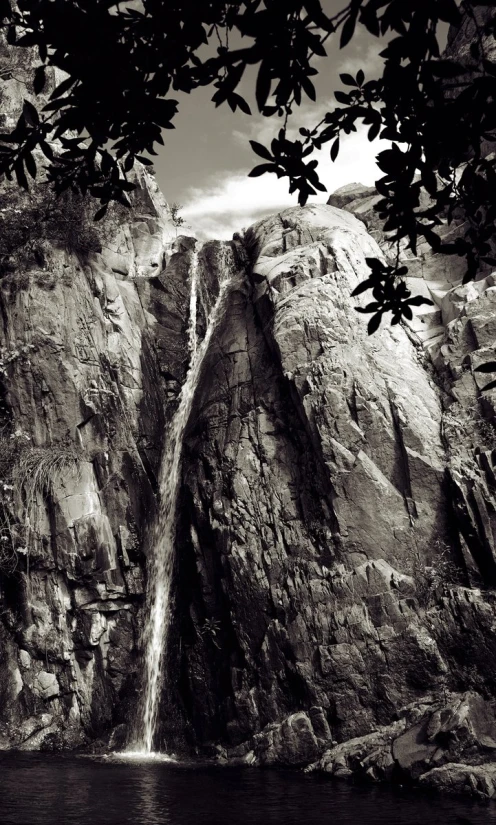 a waterfall flowing into the water from a large mountain