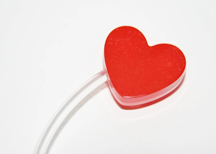 a small red heart is displayed on a white surface