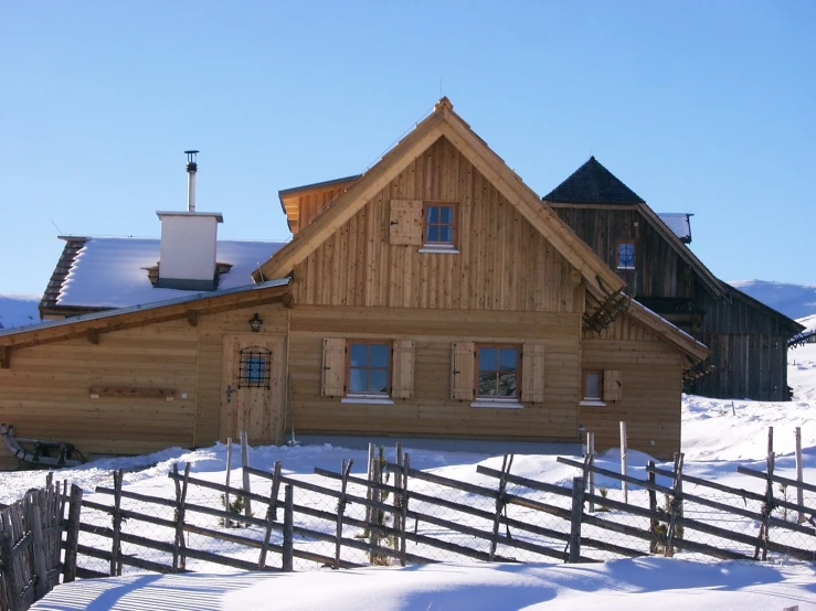 a wooden building with a small fence in the snow