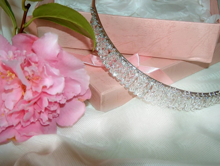 a necklace on a pink box and flowers