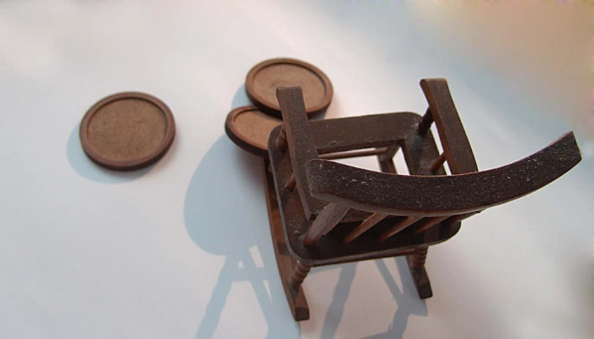 a miniature wooden chair is next to a small wooden object