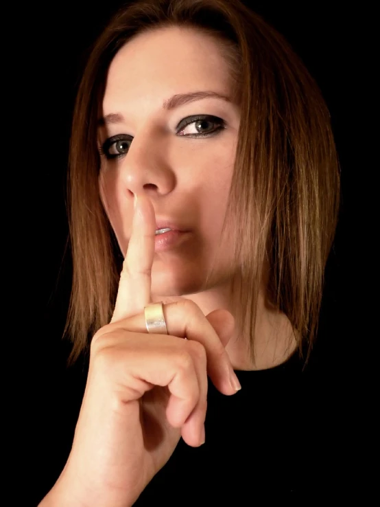 a young woman with her finger under the lip pointing at soing