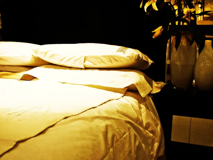 a white bed covered with pillows sitting next to some vases