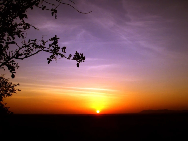 the setting sun behind some clouds in a sky