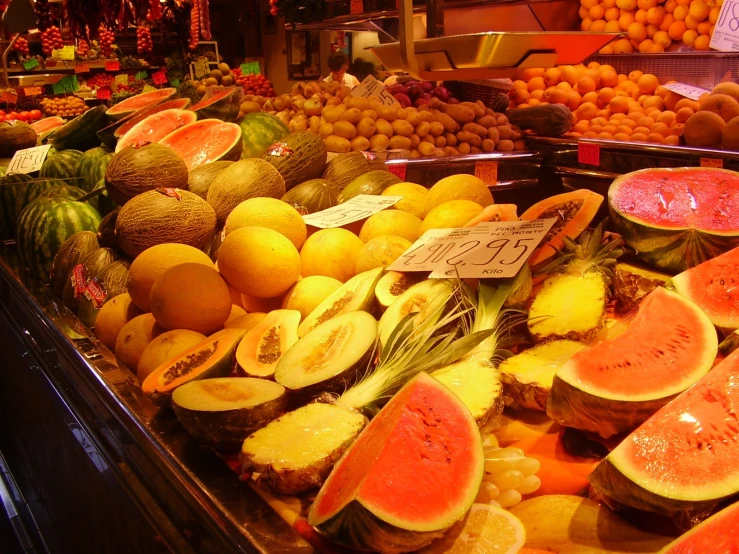 a fruit stand with watermelon, melons and pineapple