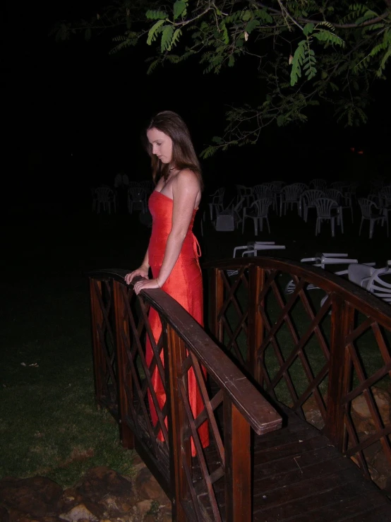 a woman in a red dress looks over a bridge