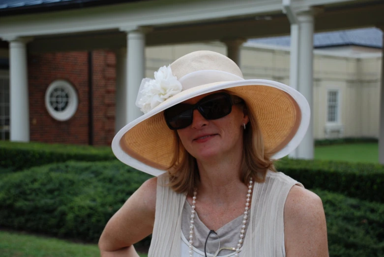 woman wearing an oversized hat and a pearl necklace