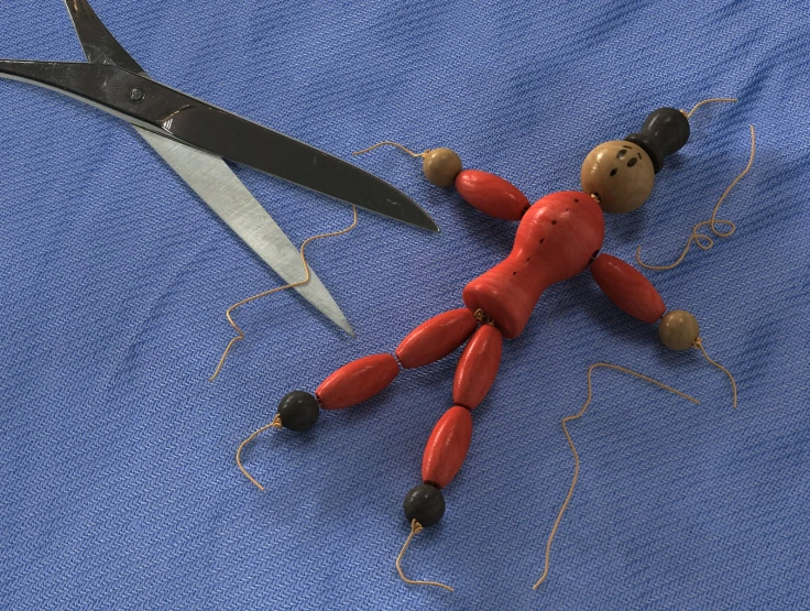 the doll is posed beside the pair of scissors