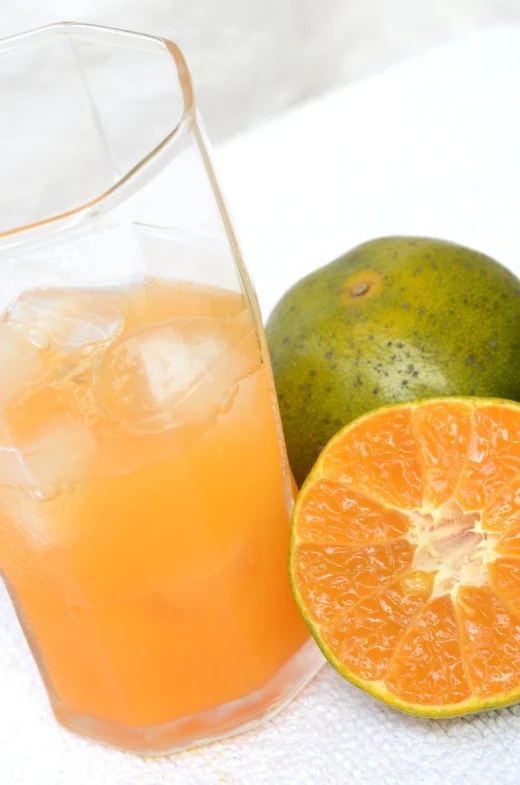 oranges and limes next to a tall glass of juice
