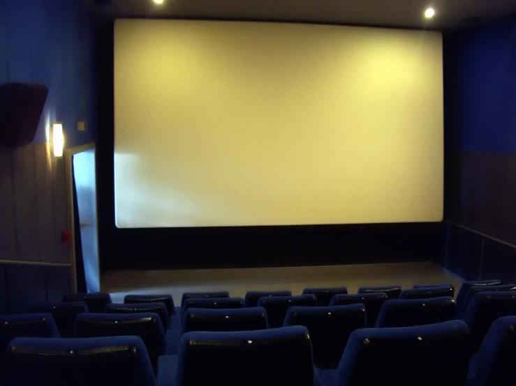 a dark room with chairs and an empty screen