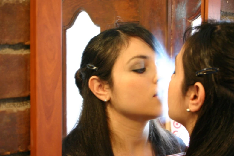 a man and woman kissing in front of a mirror