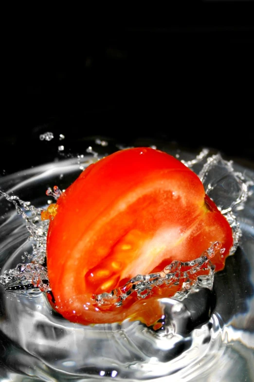 a small orange tomato floating in water with its top half over the bowl