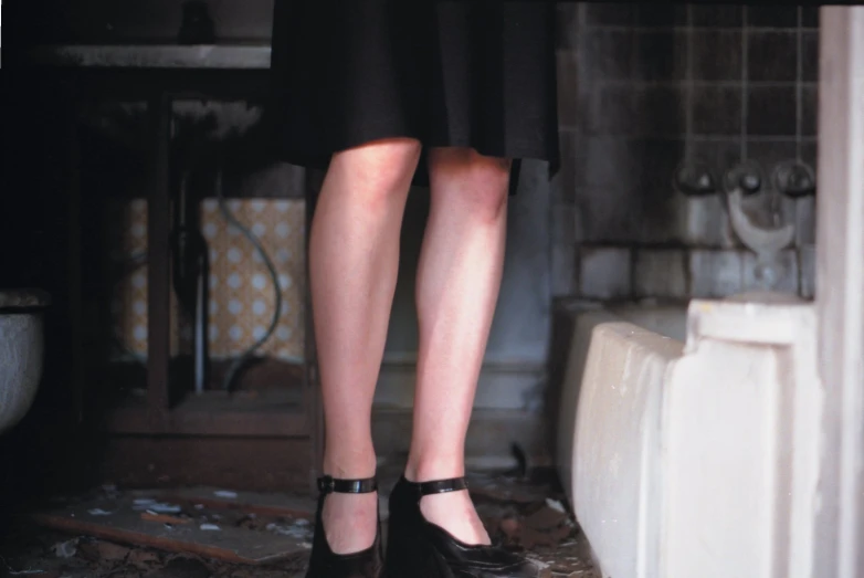 a woman wearing black high heels standing by a sink