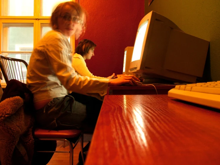 an old woman sits at her computer and looks out the window