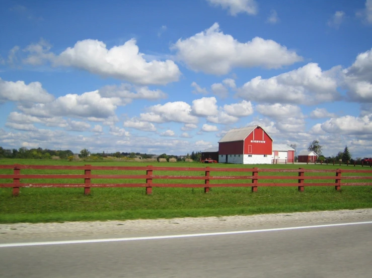 a red barn sits on a fenced pasture