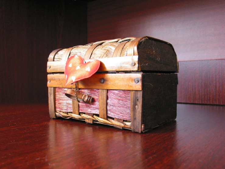 an antique wooden box that has red ribbon on top