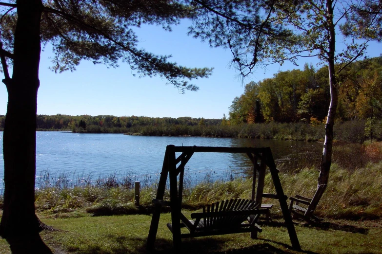 a small swing set sitting next to the side of a lake