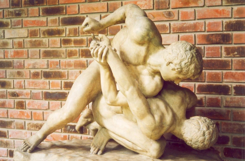 a statue of two people hugging in front of a brick wall