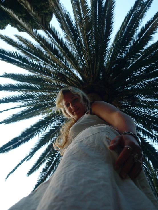 a woman in white posing beneath some palm trees