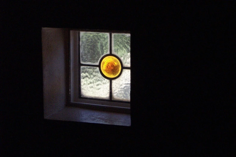 a window showing yellow and orange glass in the dark