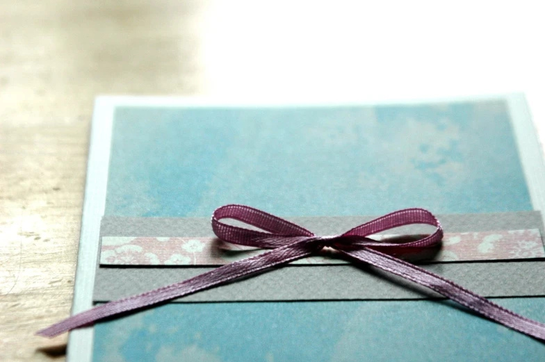 a card is wrapped in a purple ribbon