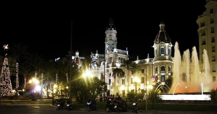 large white building in city center with fountain lit up in the dark