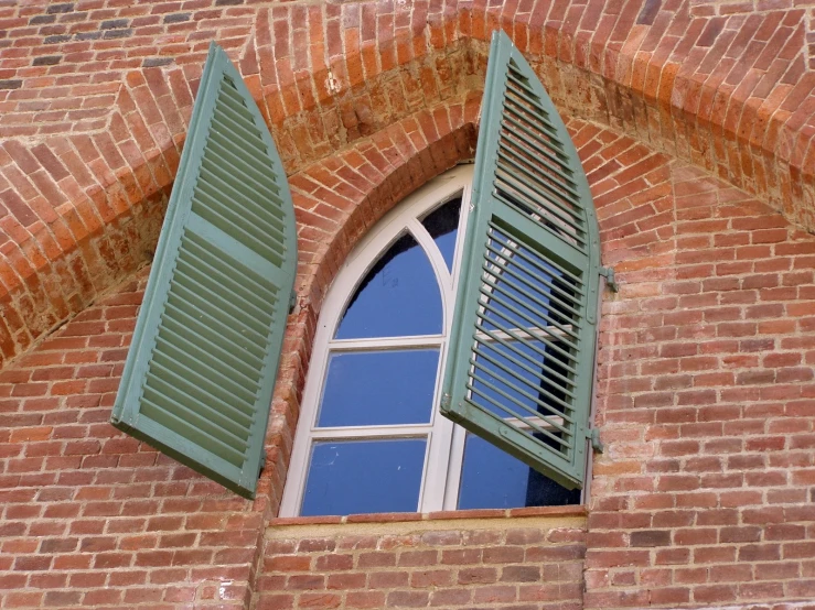 a window on a brick building with shutters