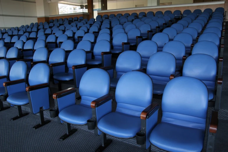 rows of blue chairs with dark wooden arm rest