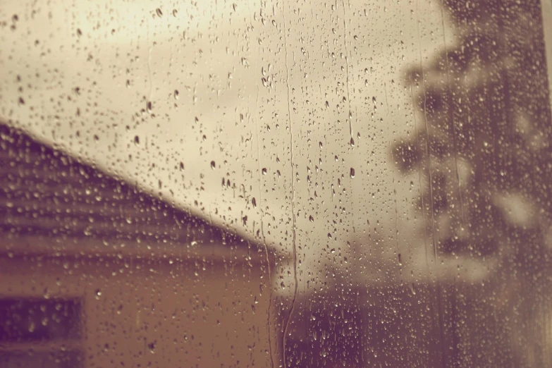 rain drops sit on a window while traffic is shown in the background