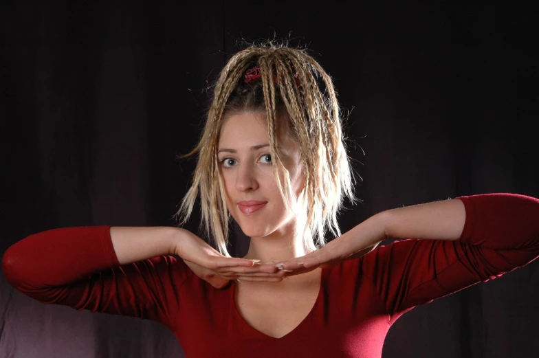 a woman with dreadlocks standing in front of a dark background