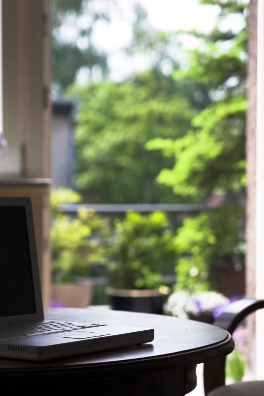 laptop sitting on a table near large open windows