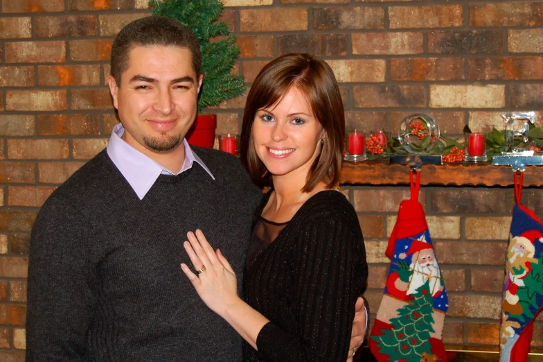 a couple is posing in front of christmas stockings